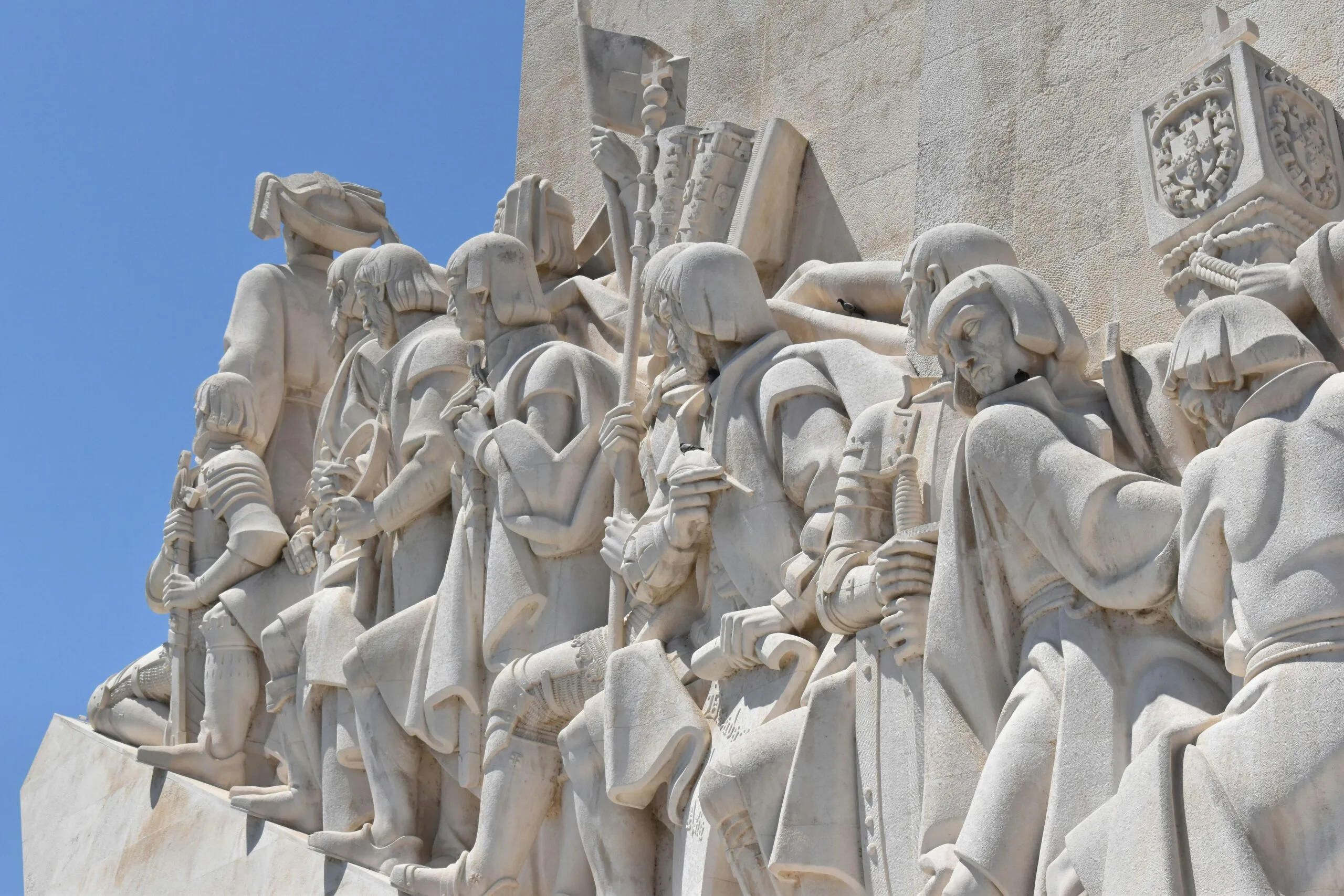 a group of statues on a wall with a blue sky in the background